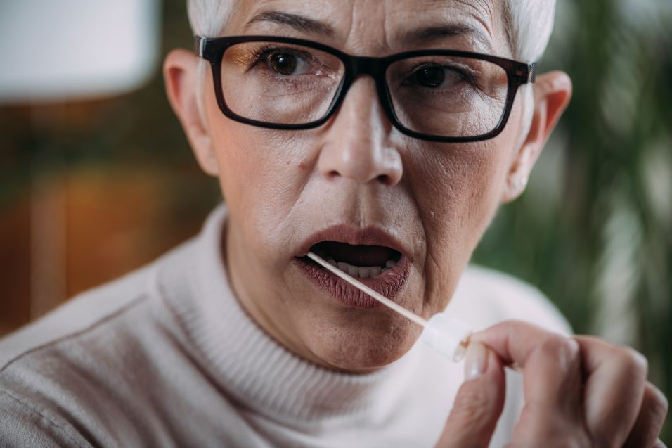 woman swabbing cheek for genetic testing