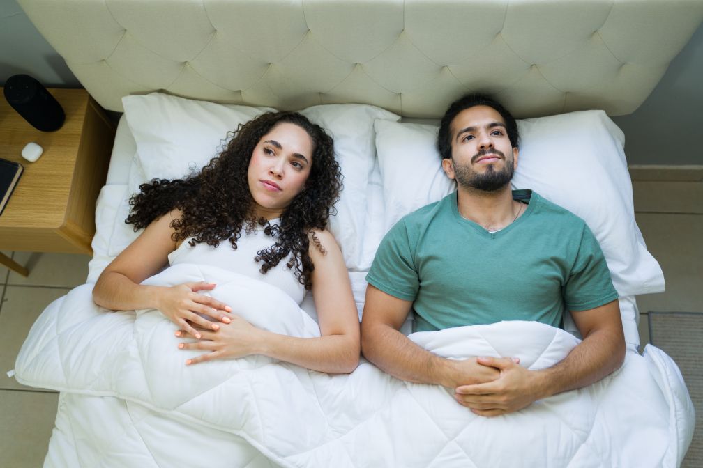 Couple lying in bed, conflicted